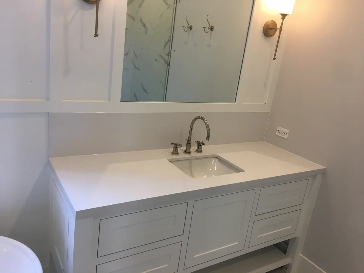 White bathroom vanity with a white counter, inset sink, and wall mirror