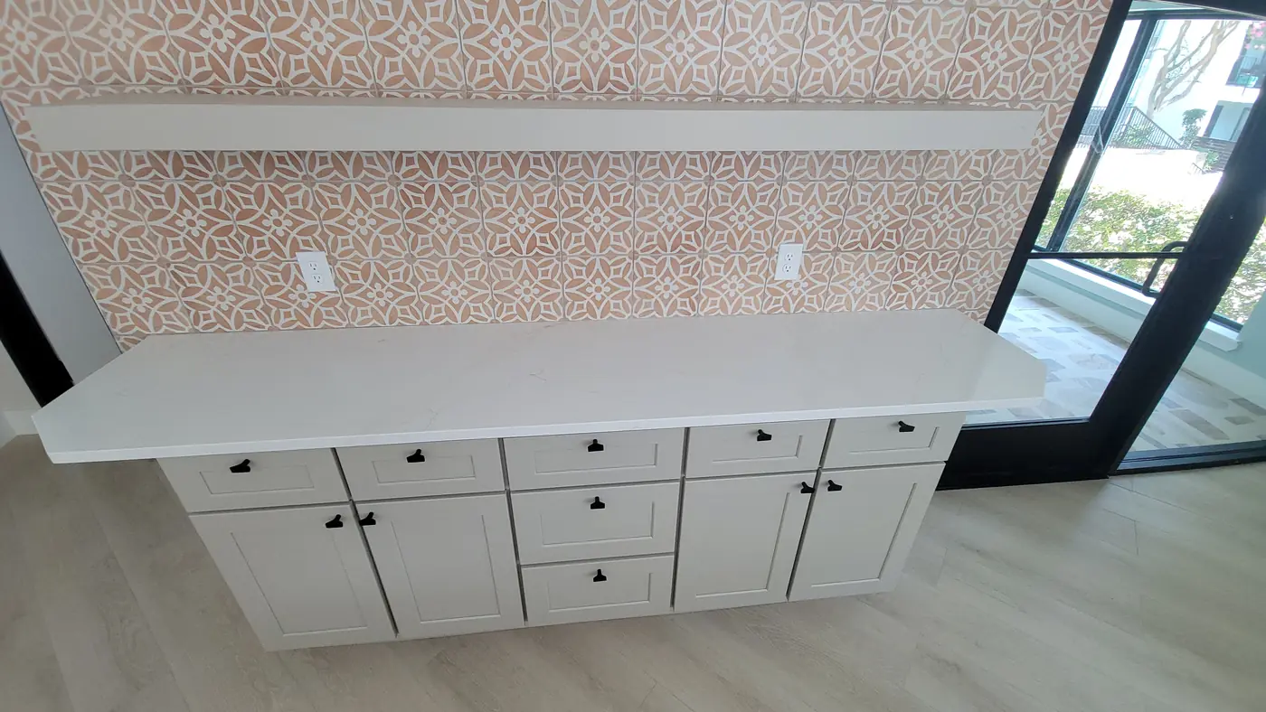 Built-in white counter beneath a patterned tile backsplash