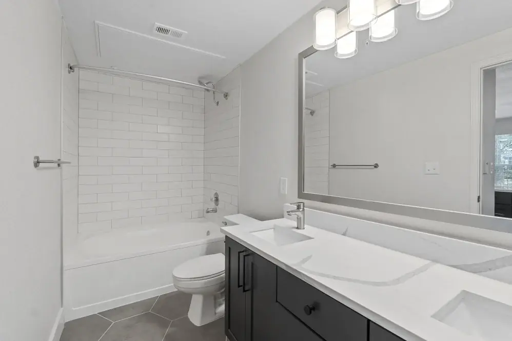 Finished bathroom with a dark vanity, white counter, tiled tub surround, and hexagonal floor tile